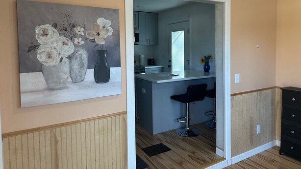 Una cocina moderna con encimera blanca, un jarrón azul con girasoles y un cuadro de flores en la pared.