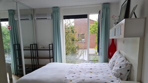 A bedroom with a bed, a desk, and a chair. There is a window with curtains, and a view of a building outside. - Clean bed & breakfast with roofterrace in Amsterdam! (Amsterdam)