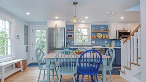 A kitchen with a dining table, chairs, and a staircase leading to another level. - Charming 3-bedroom cottage with WiFi, AC in Rochester (Rochester)