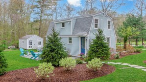 A two-story house with a blue door and a small attached garage. - Charming 3-bedroom cottage with WiFi, AC in Rochester (Rochester)