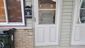 A residential building with a white door, a mailbox, and a trash can. - Charming 3-bedroom townhome in Pleasant Des Plaines with AC, WiFi (Des Plaines)