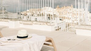 A terrace with a white table, a hat, and a railing overlooking a cityscape. - Casalta by Wonderful Italy (Ostuni)