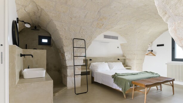 A bedroom with a stone ceiling, a bed, a bedside table, a hanging light, and a window. - Casalta by Wonderful Italy (Ostuni)