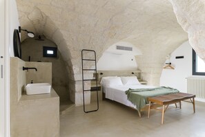 A bedroom with a stone ceiling, a bed, a bedside table, a hanging light, and a window. - Casalta by Wonderful Italy (Ostuni)