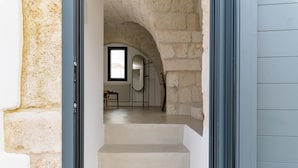 A staircase leading to a room with a stone wall, a window, and a radiator. - Casalta by Wonderful Italy (Ostuni)