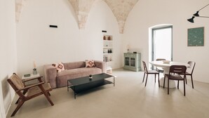 A modern living room with a sofa, coffee table, and dining area with chairs. - Casalta by Wonderful Italy (Ostuni)