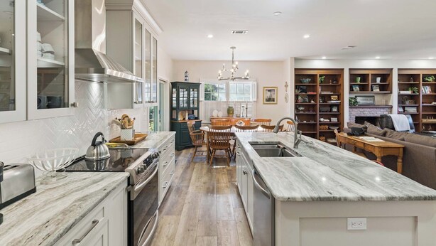 A modern kitchen with a central island, built-in cabinets, and a dining area with a chandelier. - Serene Retreat on East Beach sleeps 6 guests (St Simons Island)