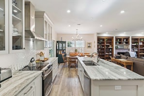 Una cocina moderna con una isla central, armarios empotrados y un comedor con candelabro.