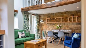 A cozy living room with a green sofa, a wooden coffee table, and a blue armchair. There's a stone wall with a built-in shelf and a fireplace. - Cherry Cottage Nr Grantley Hall (Grantley)
