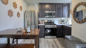 A modern kitchen with dark cabinets, stainless steel appliances, and decorative wall art.
