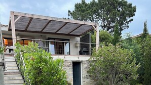 A modern house with a stone facade, a wooden staircase, and a well-maintained lawn.