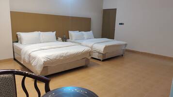 A hotel room with two beds, a wooden headboard, a round table, and a chair.