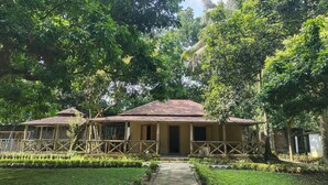 A traditional building with a tiled roof, surrounded by lush greenery and a well-maintained garden. - Kazi Resort & Hotel (Kapasia)