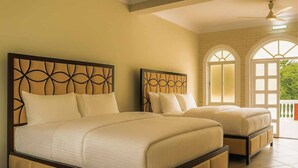 A hotel room with two beds, a balcony, and a view of greenery. - Kazi Resort & Hotel (Kapasia)