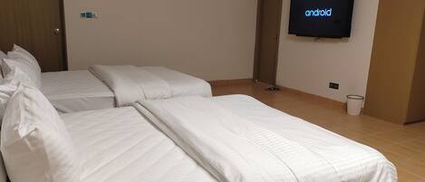 Una habitación de hotel con dos camas, un televisor montado en la pared y una puerta.