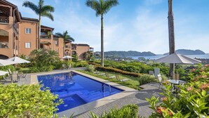 Área da piscina do resort, com vista clara para o oceano e colinas ao fundo.
