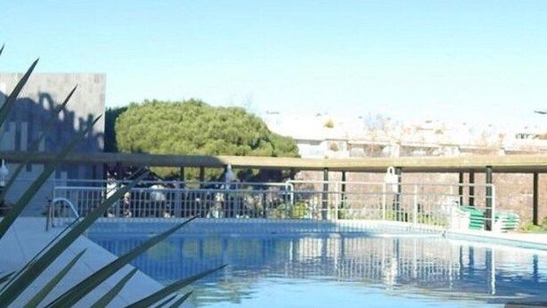 Une piscine offrant une vue dégagée sur les environs, notamment sur les bâtiments et la végétation.