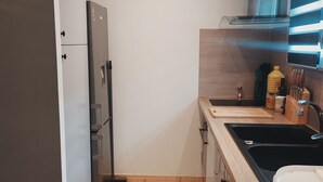 Eine kleine Küche mit Kühlschrank, Spüle und Holzschränken.