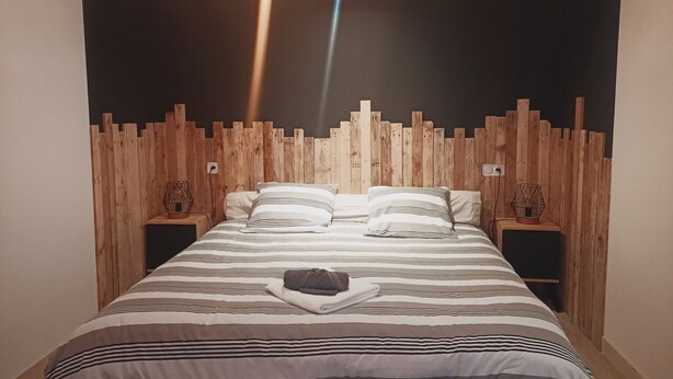 Ein Bett mit gestreifter Bettdecke, einem Holz-Kopfteil und zwei Nachttischen mit Dekoration.