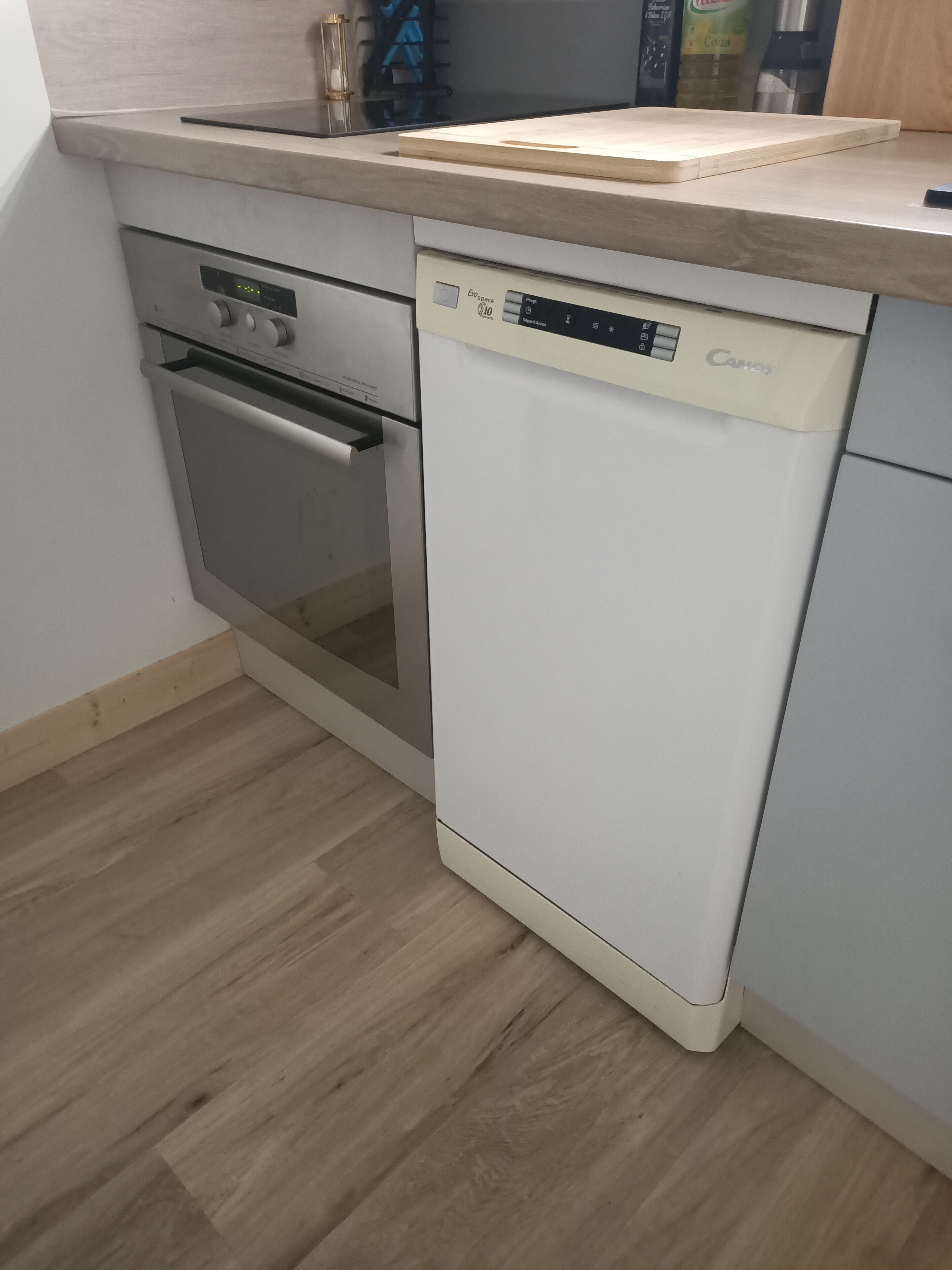 Una cucina compatta con forno a incasso, lavastoviglie e piano di lavoro in legno.