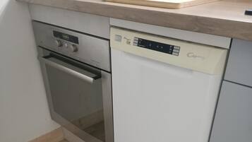Una cucina compatta con forno a incasso, lavastoviglie e piano di lavoro in legno.