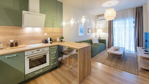 A modern kitchen with a built-in oven, a wooden countertop, and a green dining area with a table and chairs. - Mandarin apartments by halu! (Thessaloniki)