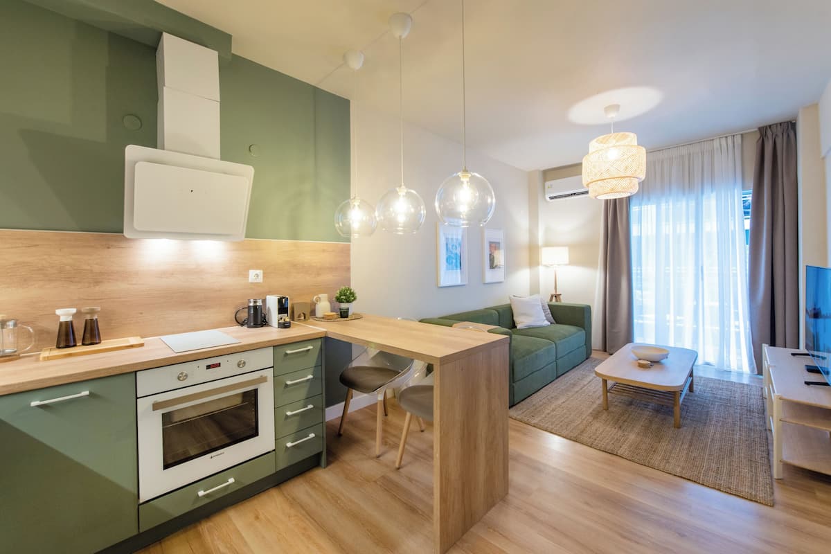 Eine moderne Küche mit Einbauofen, einer Holz Arbeitsplatte und einem Essbereich in Grün mit Tisch und Stühlen.