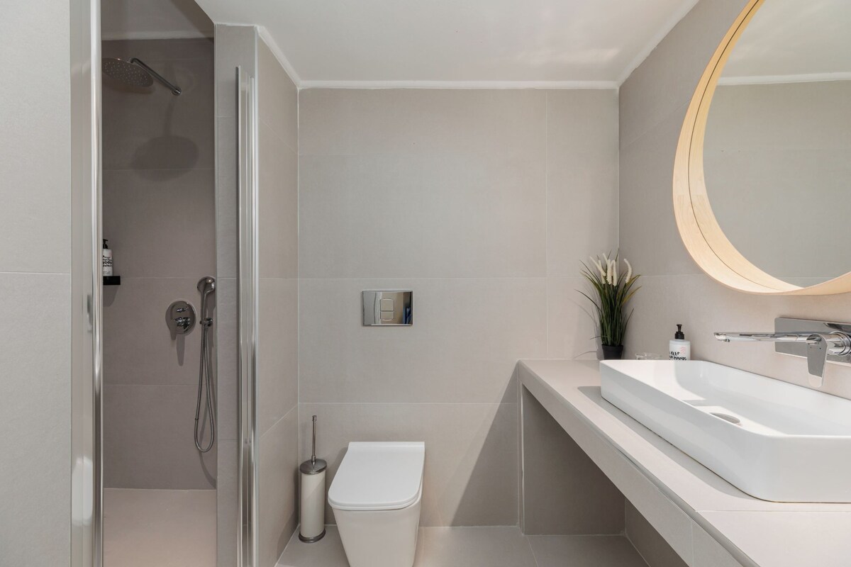 A modern bathroom with a shower, toilet, and sink.
