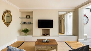 Ein Wohnzimmer mit Fernseher, Bücherregalen, Kamin und Spiegel.