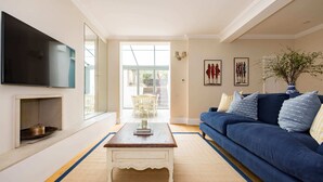 Ein Wohnzimmer mit blauem Sofa, Couchtisch, Flachbildfernseher und großem Fenster.