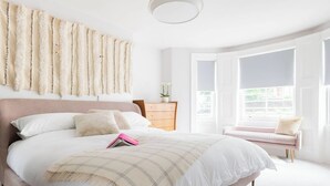 Un dormitorio con una cama grande, una mesita de noche, un aparador y una ventana con vistas a zonas verdes.