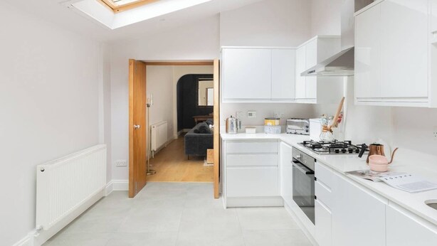 Una cocina compacta con muebles blancos, estufa a gas y tragaluz.