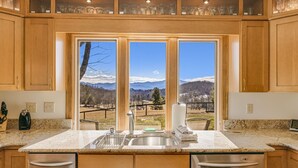 A kitchen with a large window, granite countertop, stainless steel sink, and wooden cabinets. - Daisy Farm | Pool, Hot Tub & Animals 🐴 + Biltmore Pass Near Asheville (Candler)
