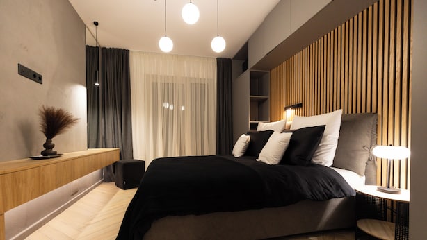 Un dormitorio moderno con cama, mesita de noche y estante en la pared.