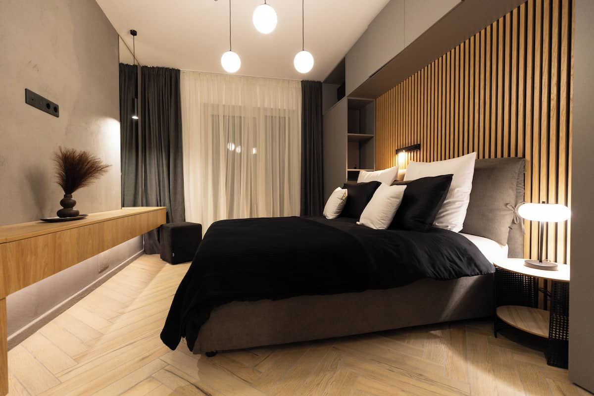 A modern bedroom with a bed, bedside table, and a wall-mounted shelf.