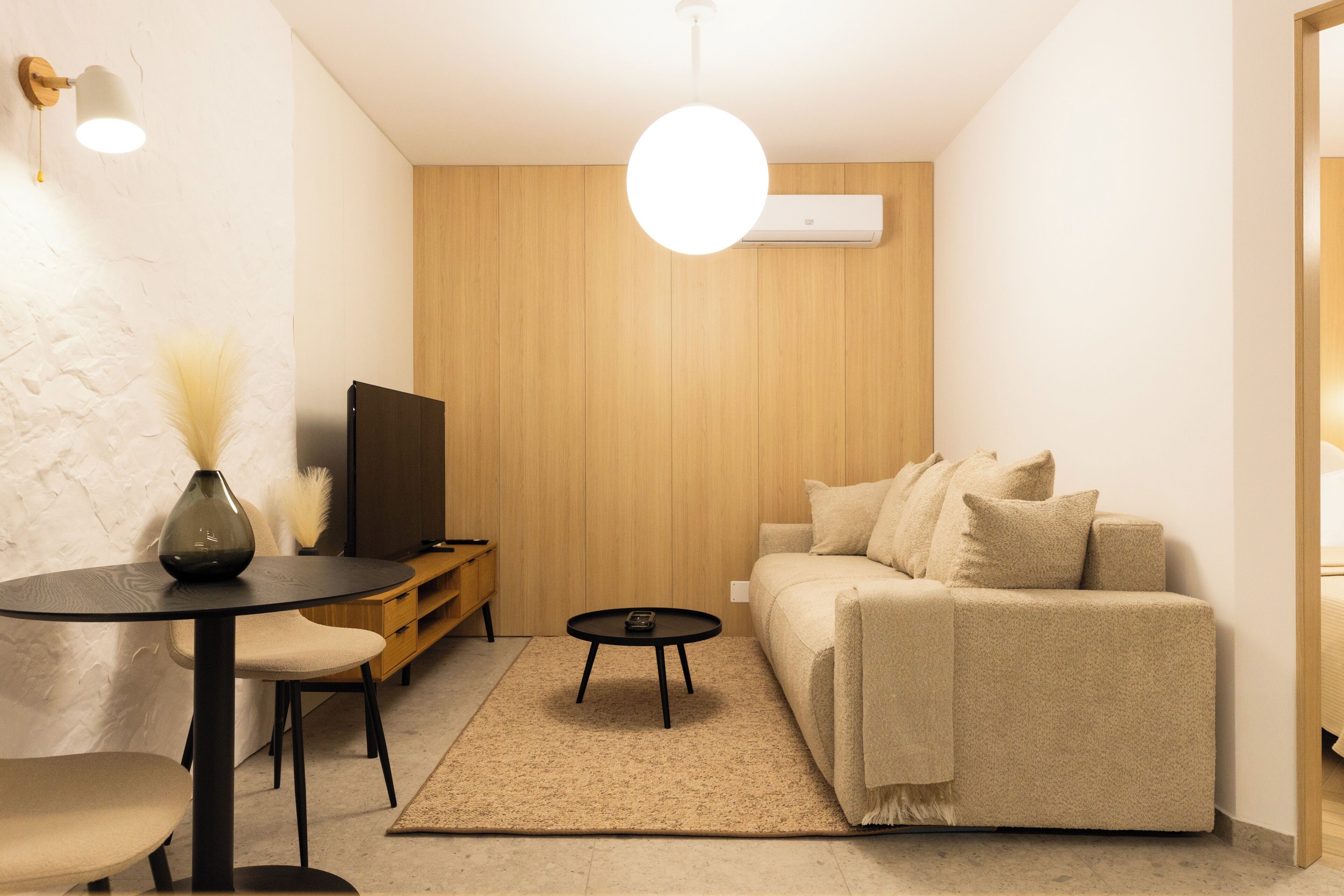 A modern living room with a sofa, a coffee table, a TV, and a lamp.