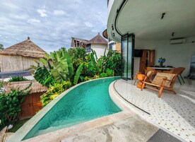 A modern villa with a swimming pool, lush tropical plants, and a dining area with wicker furniture.