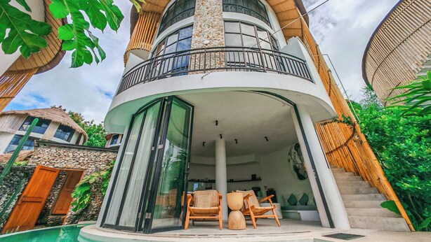 Et moderne hus med to etager, en buet balkon, en pool og en stenvæg.