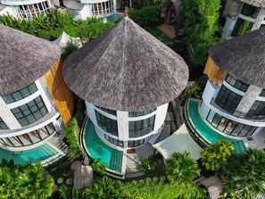 A multi-story building with a circular central tower, multiple balconies, and a swimming pool. - Hillstone Luxury Village (Ungasan)