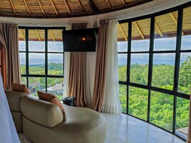 A room with a large window, a sofa, and a TV.