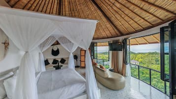 Un dormitorio con cama con dosel, un sofá, un televisor y vistas al paisaje.