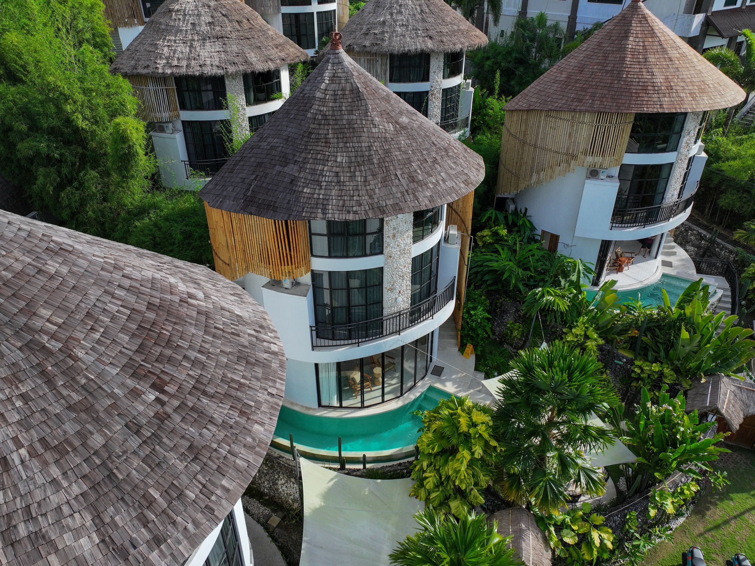 Ein Resort mit mehreren Gebäuden, jedes mit einem Reetdach und von üppiger Vegetation umgeben.