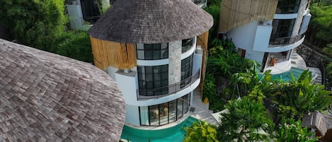 A resort with multiple buildings, each featuring a thatched roof and surrounded by lush greenery.