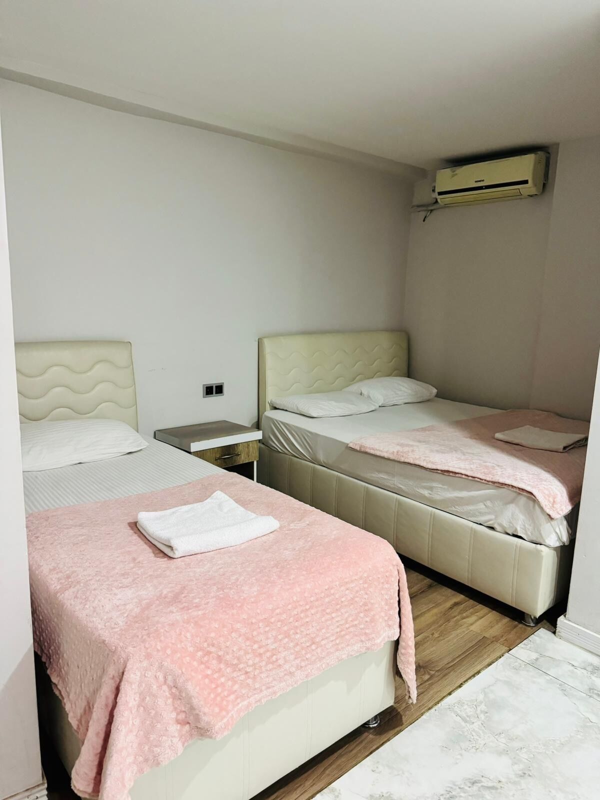 Un dormitorio con dos camas, una mesita de noche y un equipo de aire acondicionado.