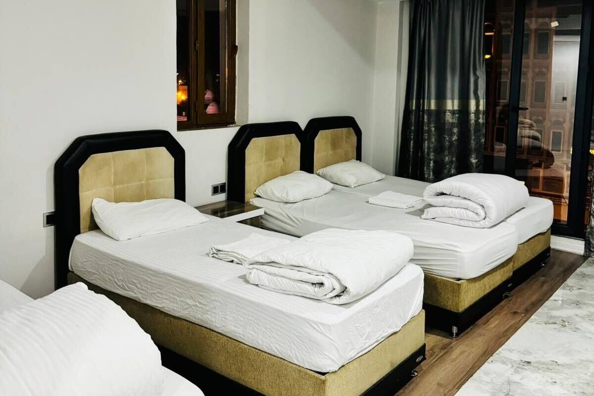 A hotel room with two beds, a window, a ceiling light, and a view of the outside.