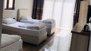 A hotel room with two beds, a desk, and a large window with curtains. - Dara Otel Midyat (Midyat)