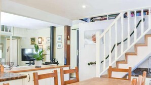 A dining area with a wooden table and chairs, a television, and a potted plant. - Red Squirrel Haven 2BR House - Sleeps 4 - Parking (Hawes)