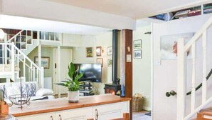 A cozy kitchen with a wooden dining table, white cabinets, and a TV. - Red Squirrel Haven 2BR House - Sleeps 4 - Parking (Hawes)