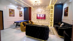 A modern living room with a pool table, a black sofa, and a yellow armchair.