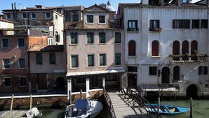 A canal-side building with a dock, a boat, and a staircase leading to an upper level. - Savoia & Jolanda Apartments  (Venice)